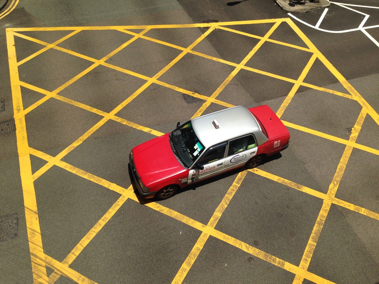 Red taxi viewed from above on a yellow-marked street